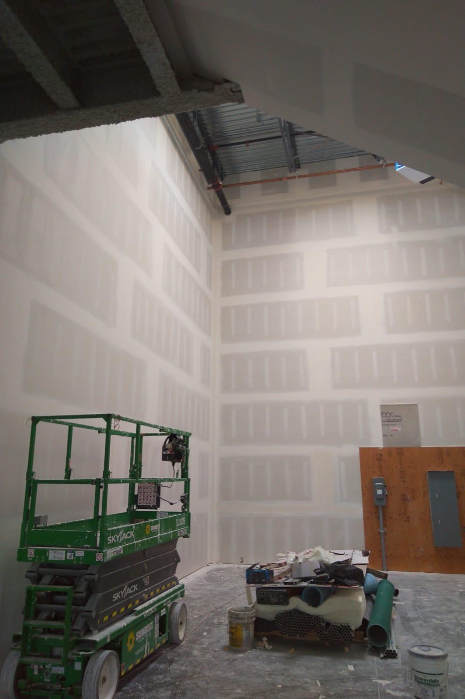 High commercial walls boarded and taped from a scissor lift